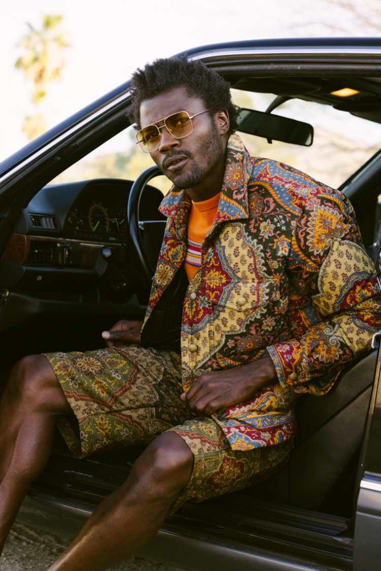 Lifestyle image by SternRep photographer Farhad Samari of a black man in colorful clothing sitting in the driver's seat of a car with the door open