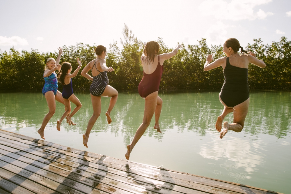 Lifestyle image by SternRep photographer Farhad Samari of a group of women jumping off a dock together into the water at sunset